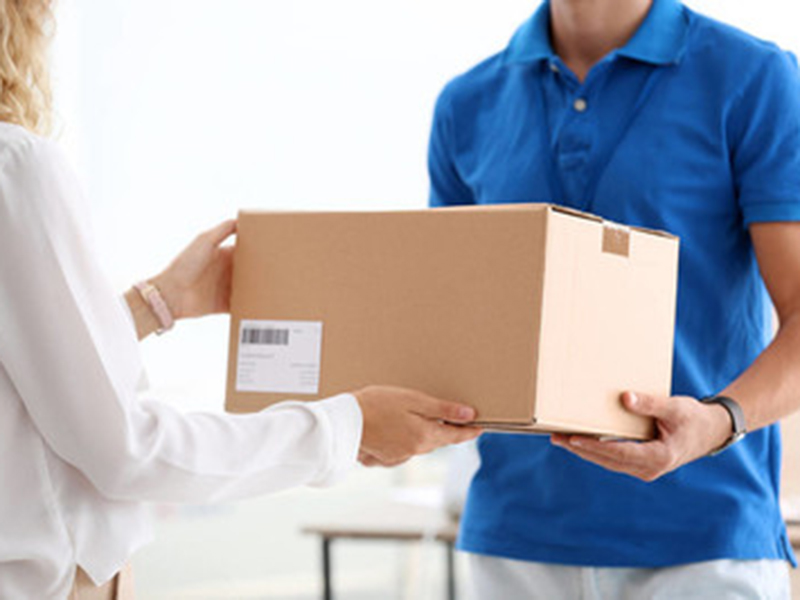 Young woman receiving parcel from courier in office